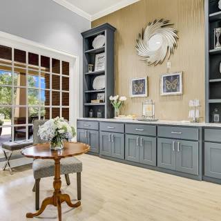 A stylish living room with modern dcor, featuring built-in shelves, a wooden table, and large windows overlooking a patio.