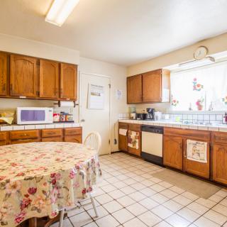 A bright kitchen with wooden cabinets and a dining table, featuring a microwave and various appliances.