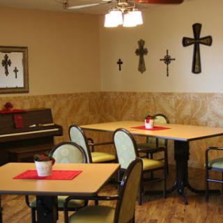 A cozy dining area featuring tables, chairs, and decorative crosses on the wall.