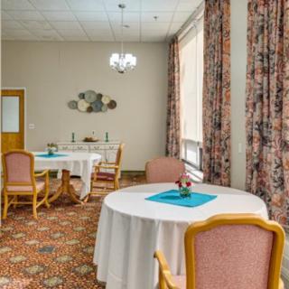 A well-furnished dining room with round tables, cushioned chairs, and decorative elements.