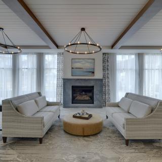 A modern living room featuring two sofas, a central fireplace, and stylish chandeliers.