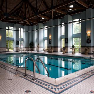 A luxurious indoor swimming pool with high ceilings and large windows.