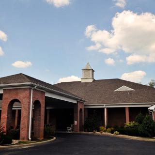 A brick building with a covered entrance under a partly cloudy sky.