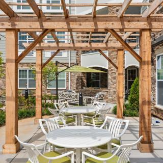 Outdoor patio area with tables and chairs under a wooden pergola.