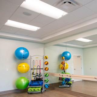 A well-lit exercise room with fitness balls and mirrors.