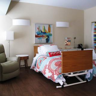 A cozy, well-decorated room featuring a hospital bed, comfortable chair, and stylish decor.