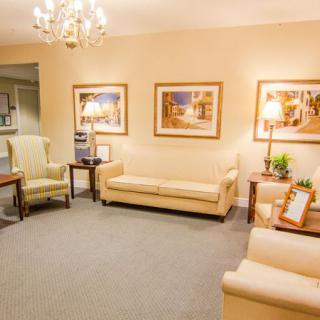 A cozy living room featuring beige sofas, wall art, and a chandelier.