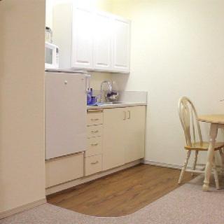 A compact kitchenette with a dining area, featuring cabinets and a small table with chairs.