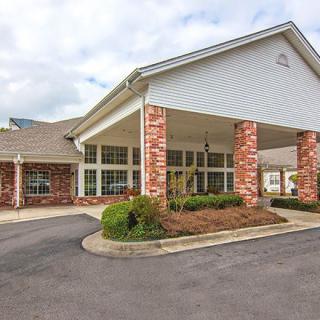 A building with a covered entrance and landscaped driveway.