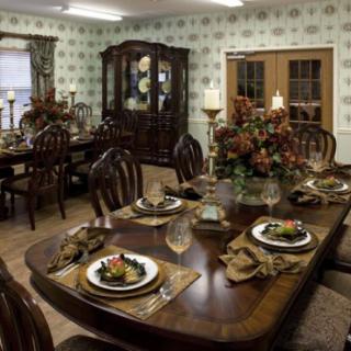 A beautifully arranged dining room with an elegantly set table, featuring decorative plates and floral centerpieces.