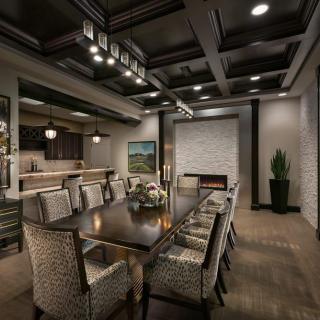 A luxurious and modern dining room with elegant decor, featuring a long table surrounded by upholstered chairs and illuminated by a stylish chandelier.