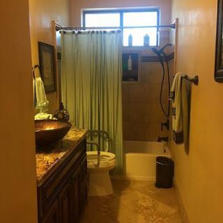 A warmly lit bathroom with a shower curtain, sink, and towel rack.