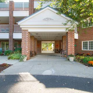 A brick building entrance with a canopy and landscaped pathway.