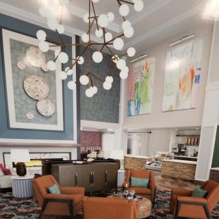 A modern lobby with stylish furniture, a large chandelier, and contemporary artwork.