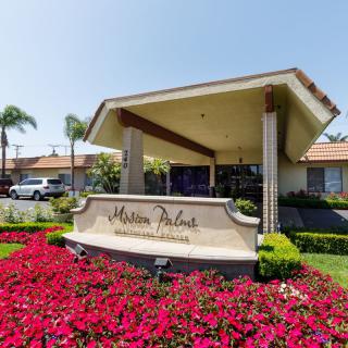 Entrance to a residential complex surrounded by vibrant flowers and greenery.