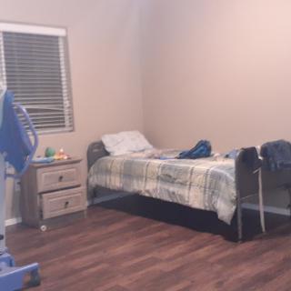 A minimalist bedroom with a single bed, nightstand, and wooden flooring.