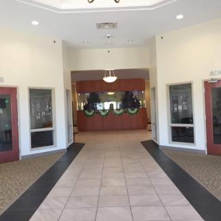 A spacious and bright lobby featuring a reception desk and glass-paneled doors.