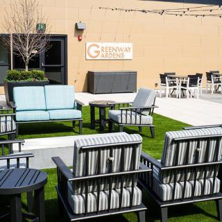 A well-furnished outdoor patio area with chairs and tables arranged on a grassy surface.