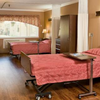 A well-lit hospital room with two beds, privacy curtains, and a warm color scheme.