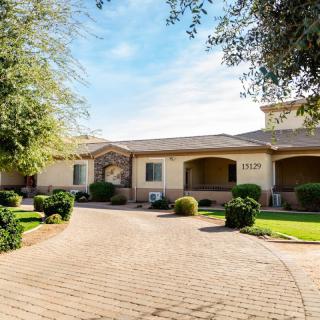 A beautiful suburban house with a landscaped yard and brick driveway on a sunny day.