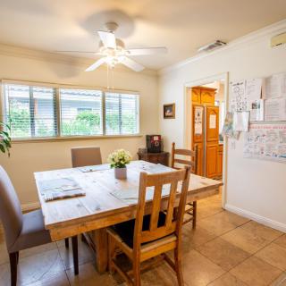 A cozy dining room with a large table, chairs, and ceiling fan.