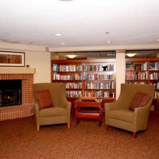 A cozy library corner featuring armchairs, a fireplace, and well-stocked bookshelves.