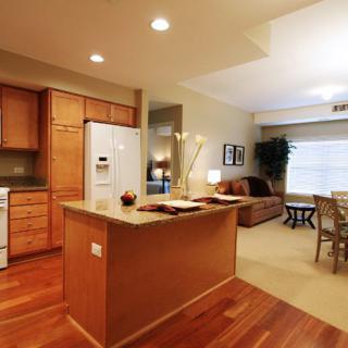 A spacious open floor plan featuring a modern kitchen with wooden cabinets and a cozy living room.