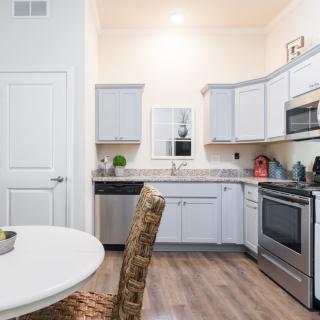 A modern kitchen with white cabinets, stainless steel appliances, and a small dining area.