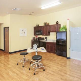 A modern office kitchenette with cabinets, refrigerator, and workspace seating.
