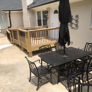 A patio area with a table, chairs, and an umbrella next to a wooden deck.