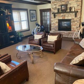 A cozy living room featuring leather furniture and a stone fireplace.