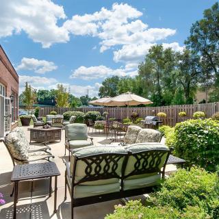A sunny outdoor patio with comfortable seating and lush greenery.