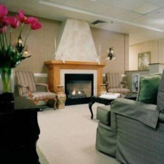 A cozy living room with a fireplace, surrounded by comfortable armchairs and a couch.