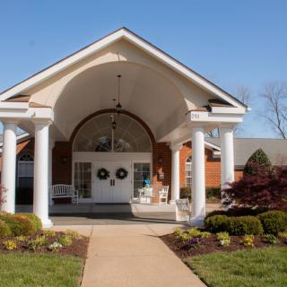 A building entrance featuring columns and well-maintained landscaping.