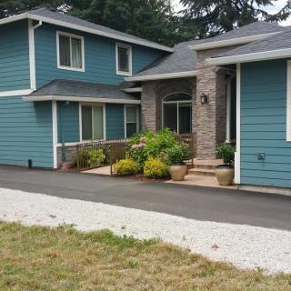 A two-story residential house with blue siding and a landscaped front yard.