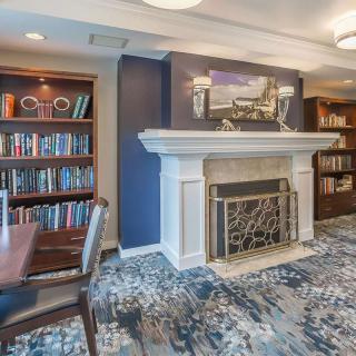 A cozy library room with a fireplace and bookshelves.