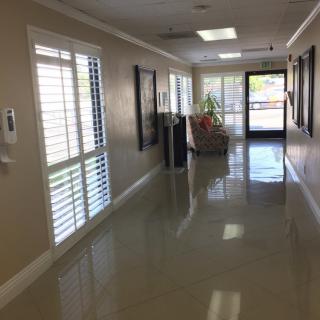 A clean, well-lit hallway with shiny floors and large windows.