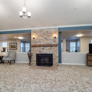 A spacious living room with a stone fireplace, carpeted floor, and cozy furniture.