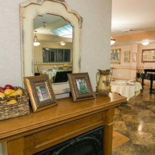 A cozy living room features a wooden mantel with framed photos and a basket of fruit, complemented by a stylish mirror.