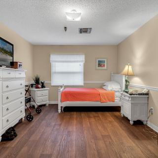 A cozy bedroom with a single bed, dresser, and warm lighting.