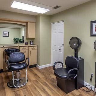 A cozy hair salon with a minimalist interior, featuring a styling chair and dryer station.