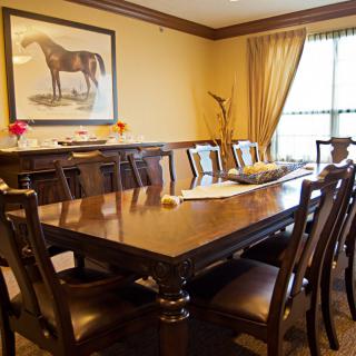 A well-furnished dining room featuring a wooden table and chairs, complemented by artwork and decor.