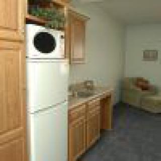 Compact kitchenette with wood cabinets and washer/dryer in a small apartment.