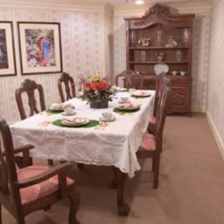 A traditionally decorated dining room with a set table and a floral centerpiece.