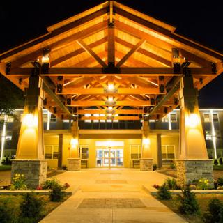 The illuminated entrance of a hotel showcasing its stunning wooden architecture at night.
