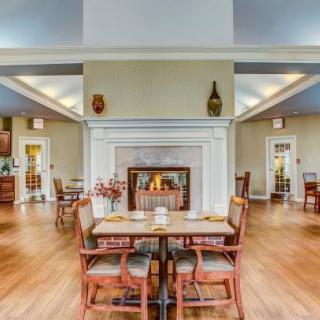 A cozy dining area featuring a central fireplace, wooden tables and chairs, and a modern interior design.