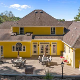 A vibrant yellow house with a spacious backyard patio area, featuring outdoor furniture under a clear, sunny sky.