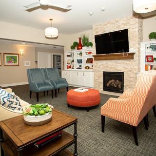A modern living room with a cozy seating area, featuring a fireplace and television.