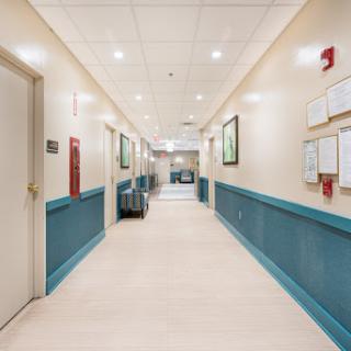 A well-lit hallway in a hospital, featuring clean walls and informative signage.