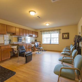 A spacious waiting room with chairs, a desk, and a kitchenette.